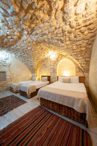 two beds in a room with a stone wall at KARAGÜL Hotel in Urfa