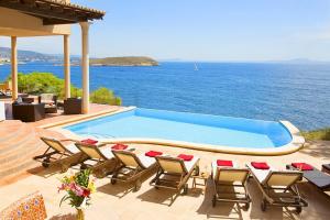 a swimming pool with chairs and a view of the ocean at Escape to Luxury: Rent Mallorca Villa 1452 in Cala Vinyes