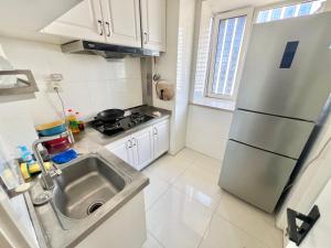 青岛Muju Qingdao Twin Family Room Near Metro Line 3 Near May Fourth Square MixC的一间带水槽和冰箱的小厨房