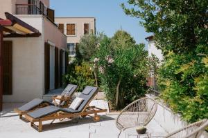a patio with two chairs and two lounge chairs at Villa Oleander by Domus Mirus - Rooftop Cinema & Pool & 6min Walk to Beach in Splitska