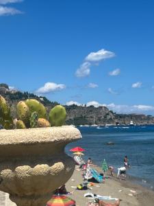 a beach with a large vase with people on the beach at Mare Blu in Giardini Naxos