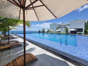 una piscina con sedie e un ombrellone di La Costa Resort Quy Nhon a Quy Nhon