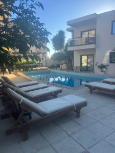 a pool with chaise lounges next to a building at NAMA Suites in Limín Khersonísou +2 photos