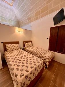 a bedroom with two beds and a flat screen tv at Le Dimore al Castello in Massafra