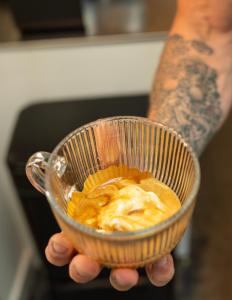 a person holding a glass cup of coffee at Nest - luxe wellness met privé sauna in Friesland in Luxwoude