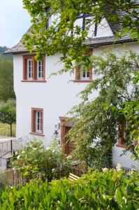 una casa bianca con finestre rosse e alberi di Weingut Bindges - Apartment Rosenhof a Traben-Trarbach
