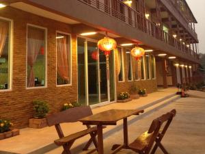 eine Terrasse mit einem Holztisch und zwei Stühlen vor einem Gebäude in der Unterkunft Kannika Place in Nakhon Phanom