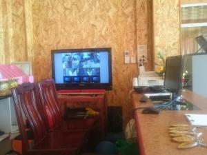 ein Wohnzimmer mit einem TV und einem Schreibtisch mit einem Tisch in der Unterkunft Kannika Place in Nakhon Phanom