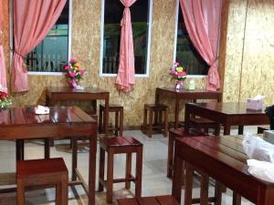 ein Esszimmer mit Tischen und Stühlen und rosa Vorhängen in der Unterkunft Kannika Place in Nakhon Phanom