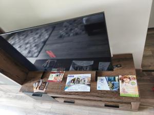 a tv screen with books and magazines on a table at Napfény Pápa in Pápa