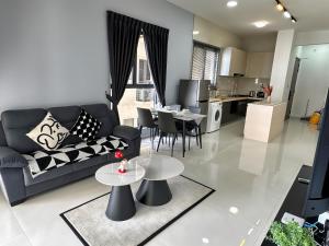 a living room with a couch and tables and a kitchen at Danga Bay Seaview Escape 3BR 8pax Balcony by Our Stay in Johor Bahru