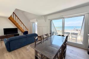a living room with a table and a blue couch at Duplex plein charme Face mer & déco moderne in Quiberon