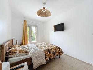 Un dormitorio con una cama y un televisor en la pared. en Villa 2 chambres avec jacuzzi, en Bonifacio