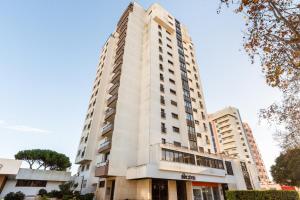 a tall white building with trees in front of it at 3BR Apt w Balcony and Sea View in Cascais