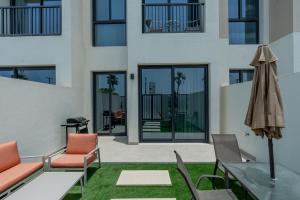 eine Apartmentterrasse mit Stühlen und einem Sonnenschirm in der Unterkunft Nasma - RAK Bliss 2BR Villa, Maid Room & Backyard in Ras al Khaimah