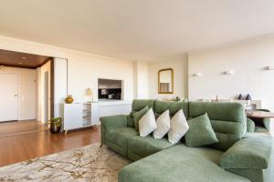 a living room with a green couch and a kitchen at 3BR Apt w Balcony and Sea View in Cascais