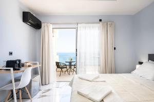コス・タウンにあるAvra Suitesの白いベッドルーム(ベッド1台、テーブル、椅子付)