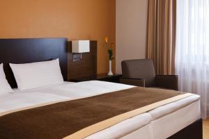 a hotel room with a bed and a chair at Steigenberger Dortmund in Dortmund +19 photos