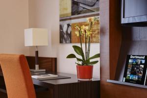 a desk with a vase with a plant on it at Steigenberger Dortmund in Dortmund