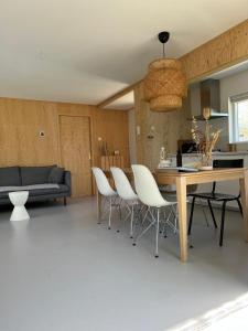 a living room with a table and white chairs at Gezellige bungalow op steenworp afstand van het strand in Ouddorp