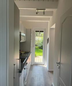 a kitchen with a hallway leading to a door with a window at Ferienhaus Deich Huus in Kappeln