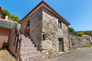 Un antiguo edificio de piedra con escaleras al lado de una calle. en Quinta Natureza de Coura, en Paredes de Coura