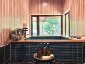 a bathroom with a tub with a window and some bottles at 森の街34# Nature Escape BBQ in Wada