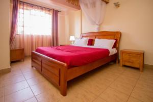 - une chambre avec un grand lit en bois et une couverture rouge dans l'établissement Ikonia Resort and Hotel, à Kisumu