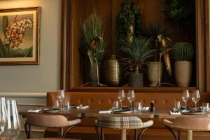 ein Esszimmer mit einem Tisch, auf dem Gläser und Pflanzen stehen in der Unterkunft Crieff Hydro in Crieff