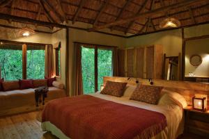 a bedroom with a bed and a couch and windows at Koroi Forest Camp in Arusha