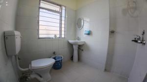 a white bathroom with a toilet and a sink at Green View Bungalow in Shillong
