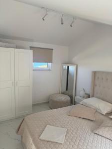 a white bedroom with a bed and a window at Perla in Stinica
