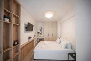 a bedroom with a white bed and a television at Lotti in Infinity Pool & Spa Resort in Mamaia