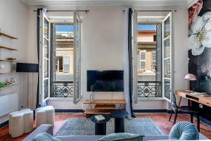 a living room with a tv and two large windows at Le Boudoir des Capucins - T2 Plein Centre Ville proche Canebière Vieux Port - Gare TGV Saint Charles in Marseille