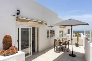 a patio with an umbrella and a table and chairs at Luxury Beach La Concha Playa Honda in Playa Honda