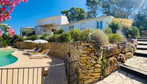 a house with a stone wall next to a swimming pool at Villa Nassalia in Lorgues