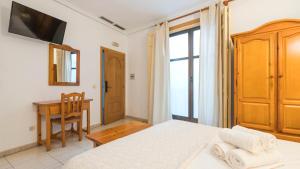 a bedroom with a bed and a table and a desk at Hostal Centro in Toledo +12 photos