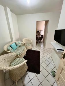 a living room with wicker chairs and a flat screen tv at 03 Apartamento Asa Branca in Caruaru