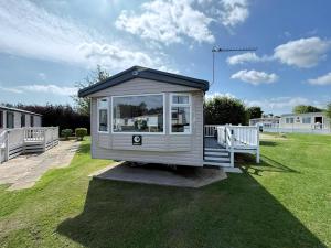 a tiny house sitting on top of a grass field at Charming 8 Berth Caravan At Cherry Tree Holiday Park In Norfolk Ref 70831C in Great Yarmouth