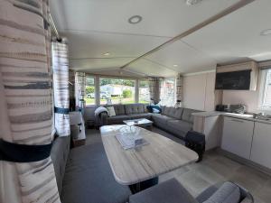 a living room with a table and a couch at Charming 8 Berth Caravan At Cherry Tree Holiday Park In Norfolk Ref 70831C in Great Yarmouth