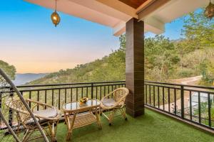 a balcony with two chairs and a table with a view at The Starlight Hotel Kasauli in Dharampur