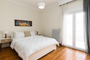 a white bedroom with a bed and a large window at Houseloft Metropolis Panorama in Thessaloniki