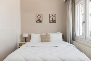 a white bedroom with a white bed and a window at Houseloft Metropolis Panorama in Thessaloniki
