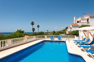 ein Swimmingpool mit Liegestühlen und Sonnenschirmen in der Unterkunft Villa Esplendor in Son Bou