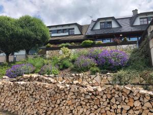 a house with a stone retaining wall and flowers at Apartmán Hájenka - Makov in Makov
