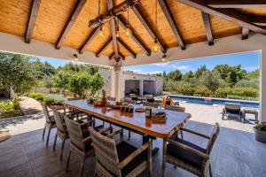 an outdoor dining room with a wooden table and chairs at Luxury Villa Nature with heated private pool, sauna & fire pit, a short walk to the beach in Milna