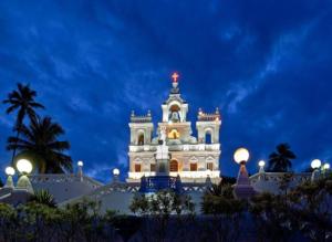 a white building with a clock tower at night at Goodstay Elegant Ocean-Themed -207 in Dabolim