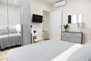 a white bedroom with a bed and a desk at Porta Napoli Holidays in Sulmona