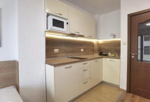 a small kitchen with white cabinets and a microwave at Cabacum Pleasure Beachfront Apartments in Varna City