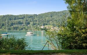 un barco en un cuerpo de agua con una montaña en Ferienwohnung 52M², en Pörtschach am Wörthersee